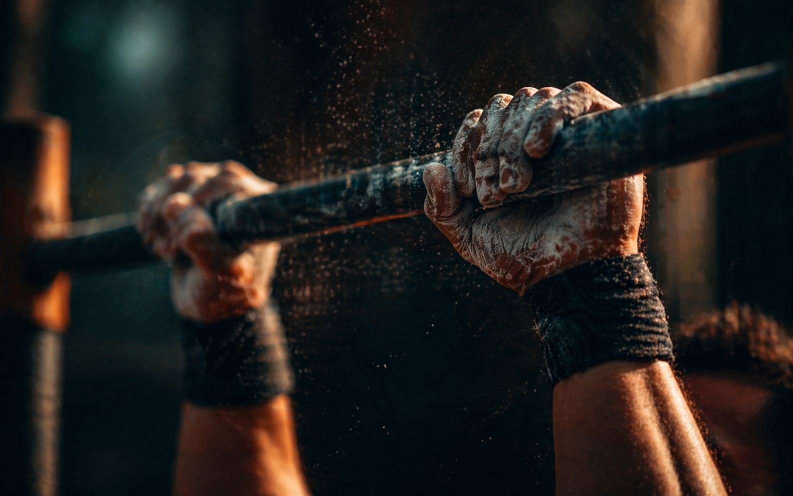 Close-up of chalked hands gripping a pull-up bar